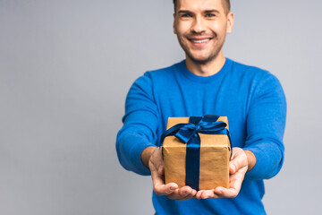 Wonderful gift! Adorable photo of attractive ukrainian man with beautiful smile holding birthday present box isolated over grey white background.