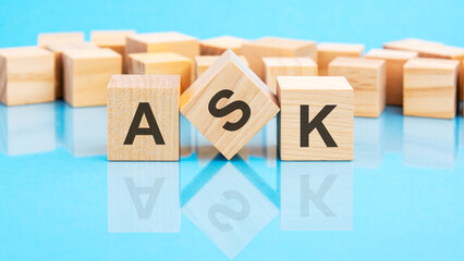 ask text is made of wooden building blocks lying on the bright blue table, concept