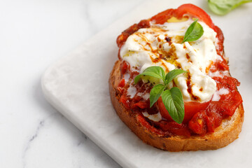 Italian grilled bruschetta with stracciatella cheese, tomatoes, oil and basil. Grilled toast, appetizer, antipasto or snack.