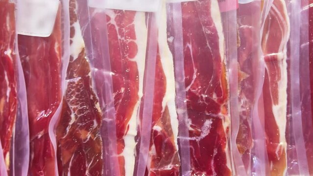 Iberian ham in vacuum plastic packs on a supermarket or grocery window. Closeup 