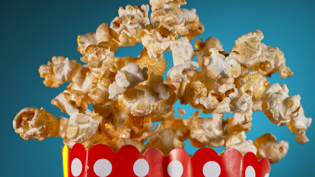 Freeze Motion of Popcorn Flying from Box on Gradient Blue Background, Close-up.