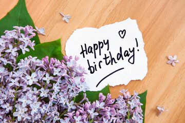 Happy birthday card with greeting lettering and bouquet of purple lilac flowers