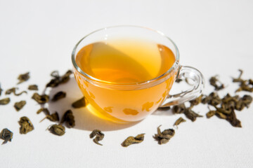 Cup of green tea with dry tealeaf on white background 