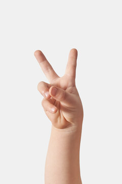 Close up of child hand victory gesturing on white.