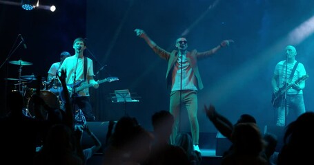 Performance of a pop or rock group, music band on stage. Stage neon light and bright strobe flashes