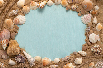 Obraz premium Marine themed frame for text. Blue background with seashells on the sand with empty space.