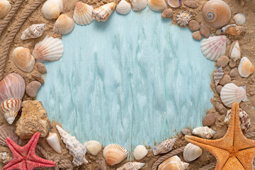 Fototapeta na wymiar Marine themed frame for text. Blue background with seashells and starfish on the sand with empty space.
