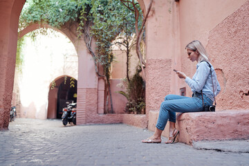 Fototapeta na wymiar Tourism and technology. Young woman using smartphone at Marrakesh old town. Traveling by Morocco.