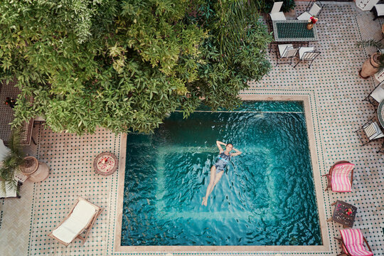 Enjoying bathing. Vacation concept. Top view of young woman in the private swimming pool in beautiful moroccan backyard.