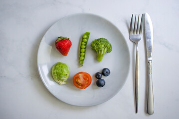 Vegetables and fruits on a plate on a light background