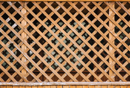 Wooden fence, lattice in rhombuses, squares close-up. Photography, background.