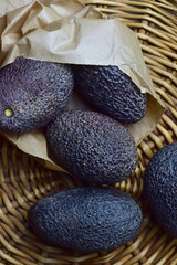 Avocados on wicker base and kraft paper bag. Zenith view and vertical shot.