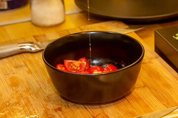 Close-up of a bowl of summer salad and a mock-up bottle of nut butter in a female hand. Oil is poured into salad