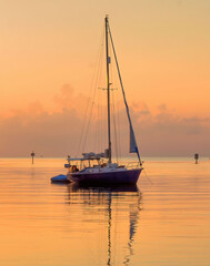 sailboat at sunrise on golden waters