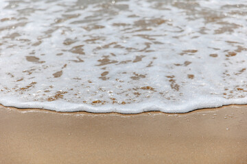 Seascape. Foam waves at sandy beach. Waterscape for background. Nature concept. Soft focus. Motion waves. Copy space.