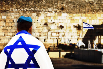 Jerusalem, Israeli Soldier with Flag of Israel in front of the blurred Western Wall on the Western Wall Plaza. Concept: IDF,  Israel Independence Day, Memorial Day for Israel's Fallen Soldiers - obrazy, fototapety, plakaty