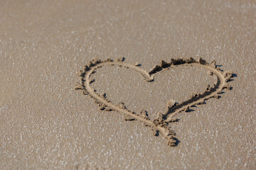 A heart painted on the sand on the seashore. Valentine's Day and all lovers.