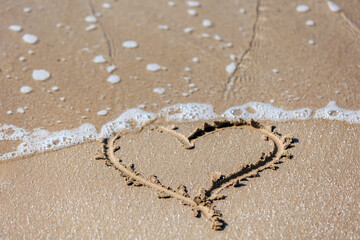 A heart painted on the sand on the seashore. Valentine's Day and all lovers.