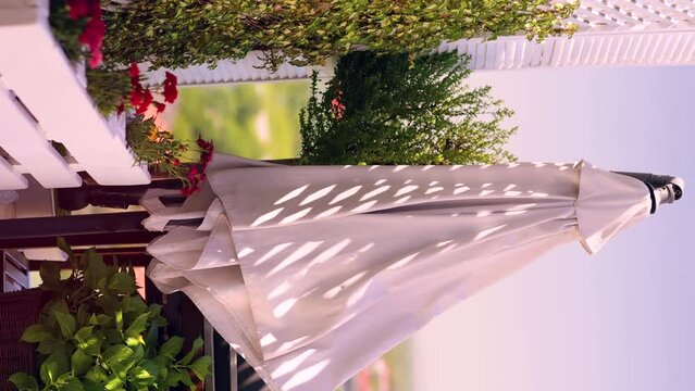 vertical video of garden umbrella swaying on the wind at the rooftop patio on warm summer day