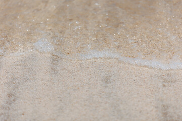 Soft wave of blue sea on sandy beach. Background. Selective focus.