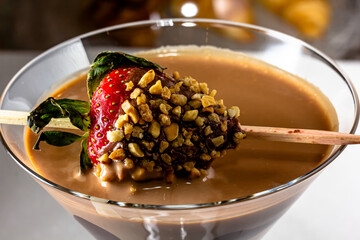 Chocolate drink with whipped cream, strawberry and pieces of black chocolate on a dark background.