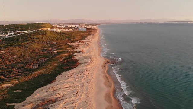 Aerial View Of A Long Sandy Beach On The Mediterranean Sea With Small Towns In The Distance At Sunset