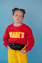 beauty portrait of stylish teenage girl in fashionable bright clothes. tween wearing red and yellow clothes on blue background. fashion portrait. two topknots. bright orange make up