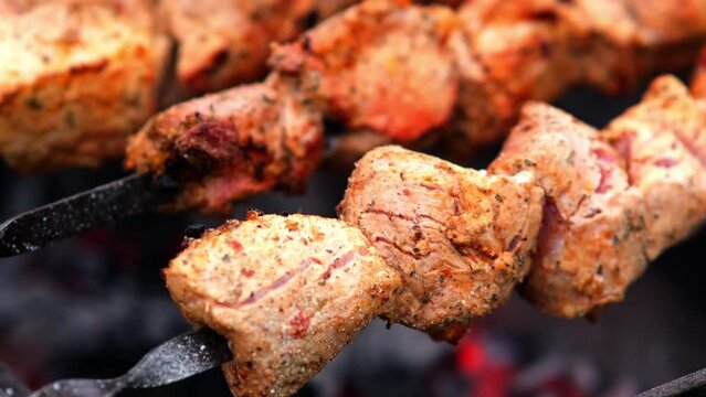 Close-up of grilling tasty dish on barbecue. Process of cooking yummy shashlik in nature. Delicious food on metal skewer in bbq. Time to picnic concept. Street food. Food festival. Pork at the stake
