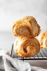 Two fresh croissants on a baking rack on a light background