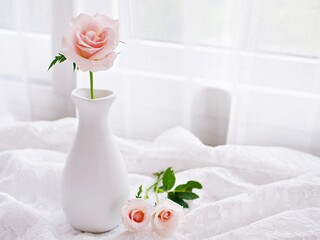 Pink pastel rose flowers in vase on table with embroidered cloth, still life for background or...