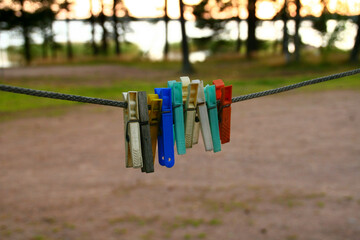 Fototapeta na wymiar Bright coloured pins on clothes line in forest with copy space. Closeup. Finland. Hamina. Golf of Finland