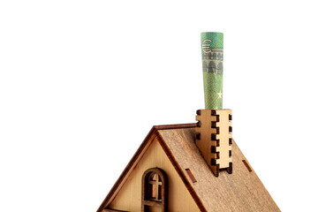 Euro bill in the chimney of wooden toy symbolic house on white isolated background. Heating concept