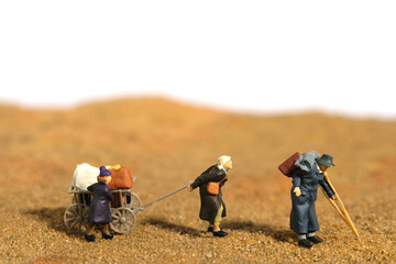 Miniature people toy figure photography. An elder couple with a grandchild refugee walking, moving...