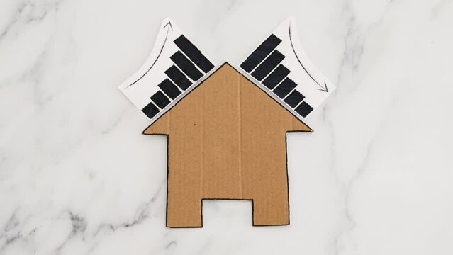 mortgages rentals and property prices increasing and decreasing, house icon made of cardboard with graph showing stats going up and down