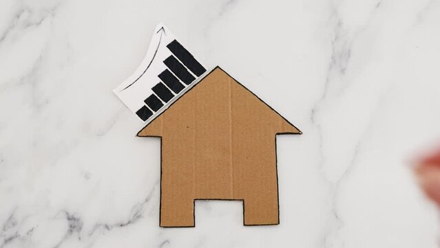 mortgages rentals and property prices increasing and decreasing, house icon made of cardboard with graph showing stats going up and down