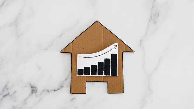 mortgages rentals and property prices increasing, house icon made of cardboard with graph showing stats going up