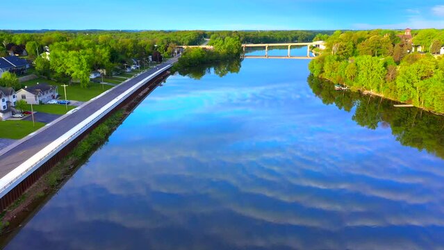 Amazing sky with rippled clouds, mirrored in tranquil river at daybreak, moving aerial view.
