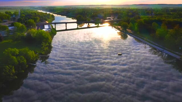 Amazing sky with rippled clouds, mirrored in tranquil river at daybreak, moving aerial view.
