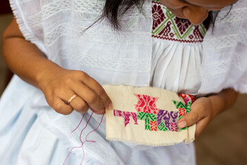 Close up of a woman embroidering traditional Mexican patterns from puebla