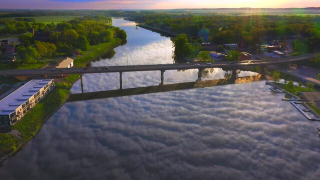 Amazing sky with rippled clouds, mirrored in tranquil river at daybreak, moving aerial view.
