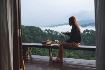 A young woman making drip coffee with a beautiful mountain and nature view in background