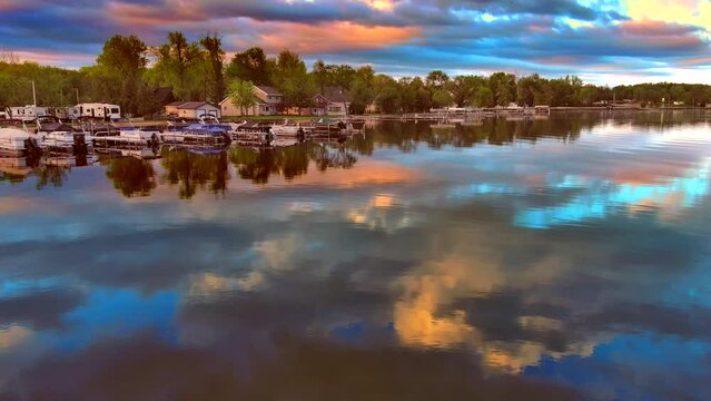 Amazing colorful clouds and sky reflected in tranquil lake at daybreak.