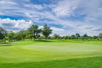 Fotobehang Een uitzicht landschap groen gras op de golfbaan, grote bomen met zonlicht hemelachtergrond. © APstudio
