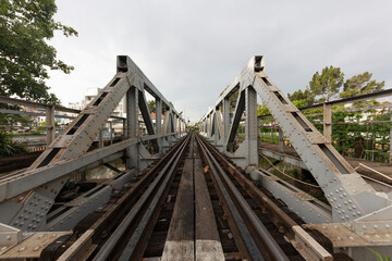 Fototapeta na wymiar Old French Colonial railway bridge crossing a canal in Saigon or Ho Chi Minh City, Vietnam. Perspective is looking along the tracks