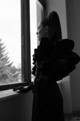 a young girl in an evening dress at the window 