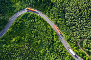 Fototapeta Transporting wind turbine propeller through curvy jungle road. Clean alternative energy to reduce global warming and climate change for sustainable growth. obraz