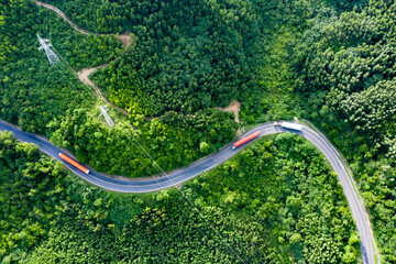 Transporting wind turbine propeller through curvy jungle road. Clean alternative energy to reduce global warming and climate change for sustainable growth.