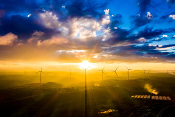 Wind turbines in a big green field at sunset generating electricity. Clean alternative energy to...