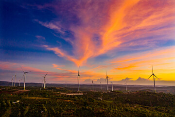 Wind turbines in a big green field at sunset generating electricity. Clean alternative energy to...