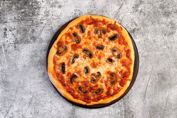 Homemade vegetarian pizza with mushrooms, cheese and tomato sauce on a round wooden cutting board on a dark grey background. Top view, flat lay